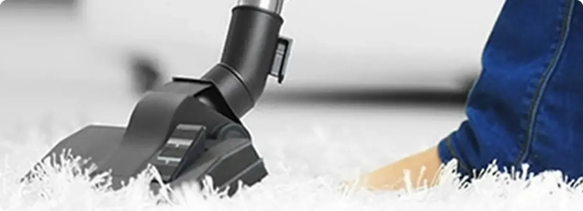 Close-up of a professional vacuuming a white carpet in Benton.
