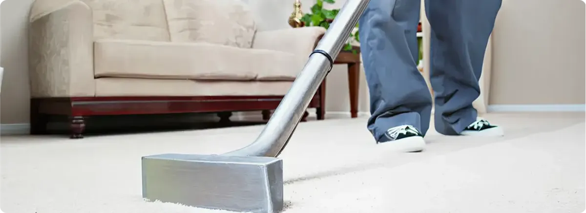 Carpet cleaning technician using a hot-water extraction wand on a light-colored carpet in a living room, Shreveport, LA.